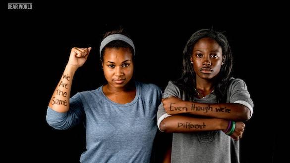 Two women with writing on arms, We Are the Same Even Though We're Different