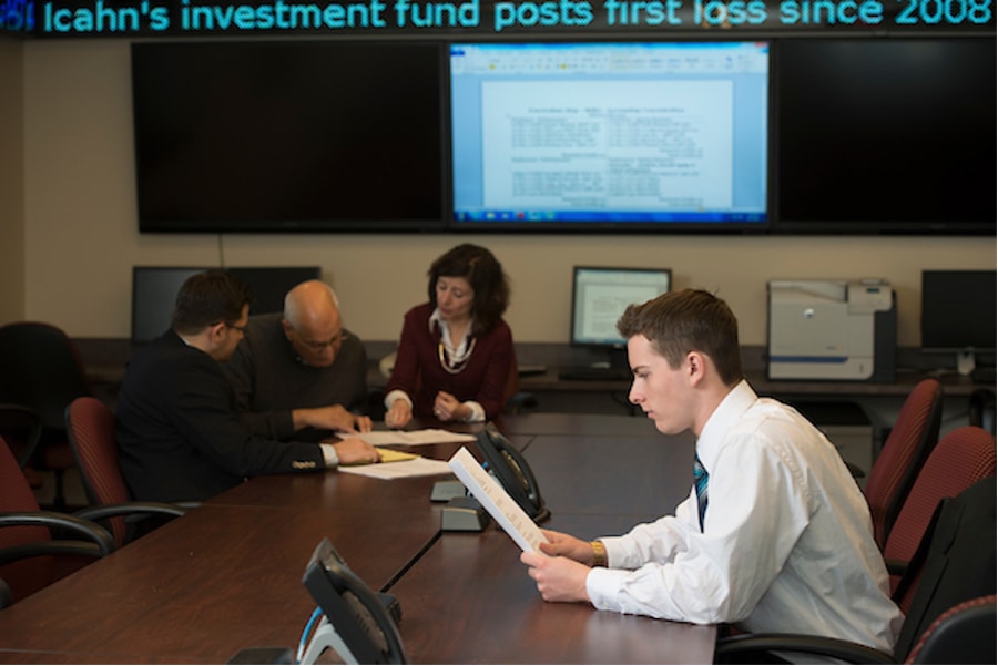 A student at a conference room with other professors