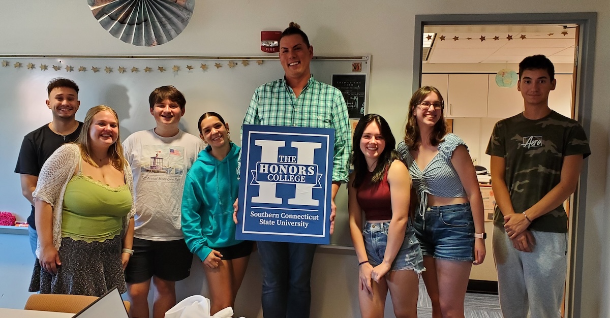 Professor holding an Honors College sign with students