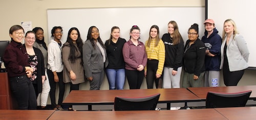 Several women in a line posing in front of.a classroom