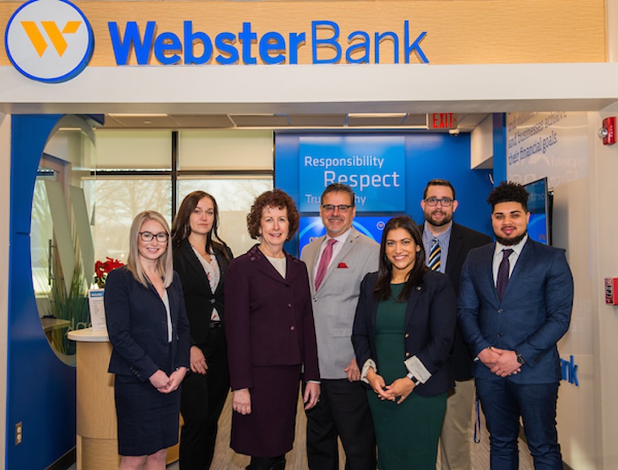 Students and faculty posing in front of a bank