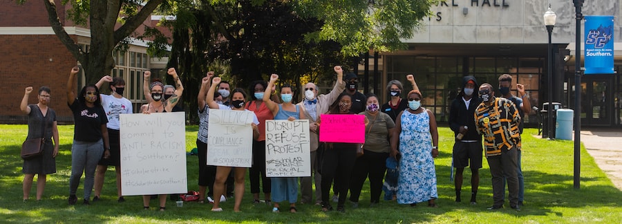 A group of faculty and staff protesting with signs on the academic quad