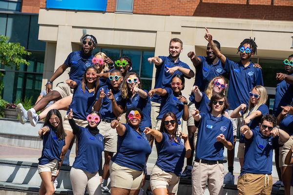 "A group of students wearing university t-shirts in front of the university library"