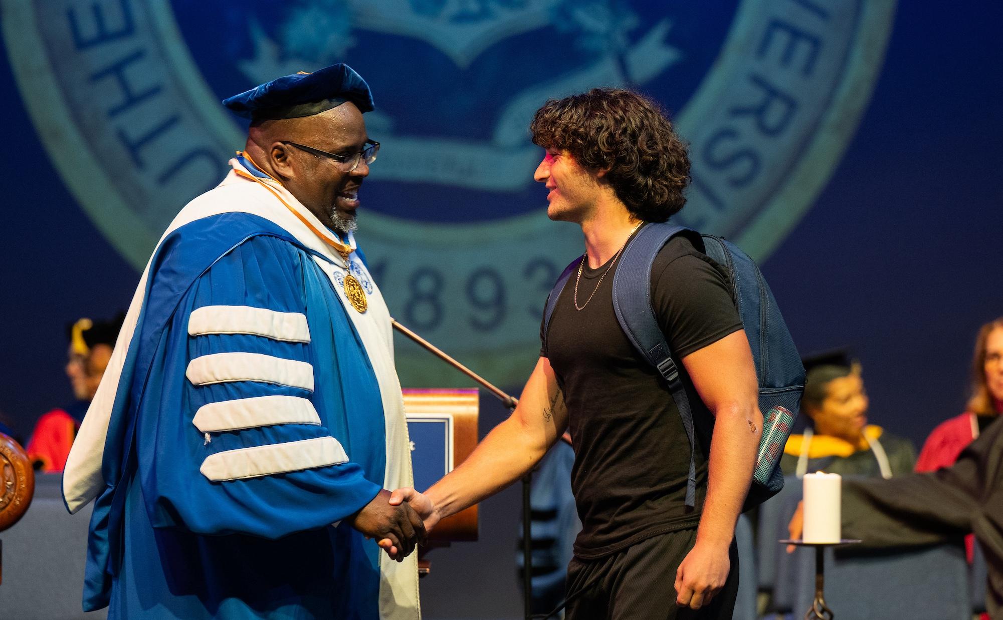 Interim President Dwayne Smith shaking Student's Hand at Convocation Event