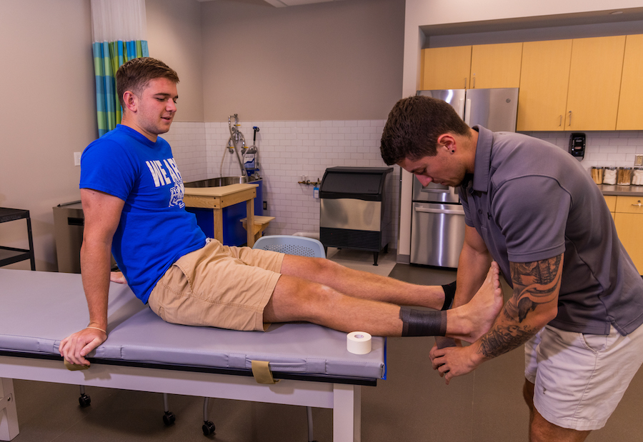 Professor applying a bandage on a student's foot as a demonstration 